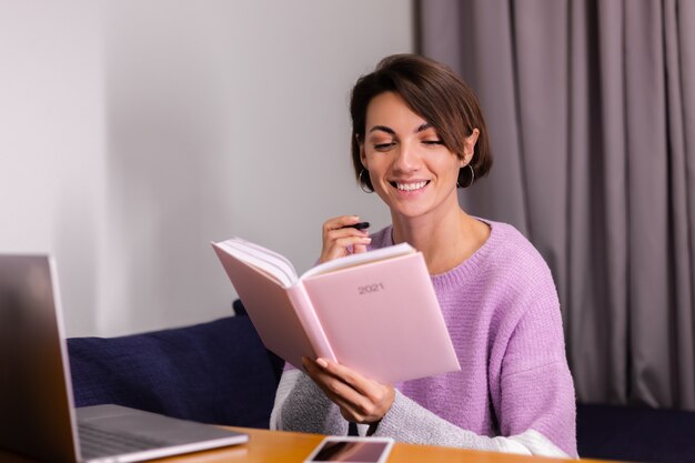 Femme à la maison avec un bloc-notes en pensant à des plans