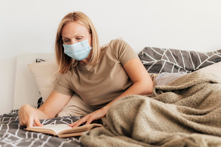Photo gratuit femme à la maison avec livre de lecture de masque médical