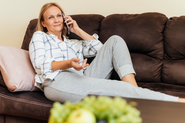 Femme à la maison pendant la quarantaine, parler sur smartphone