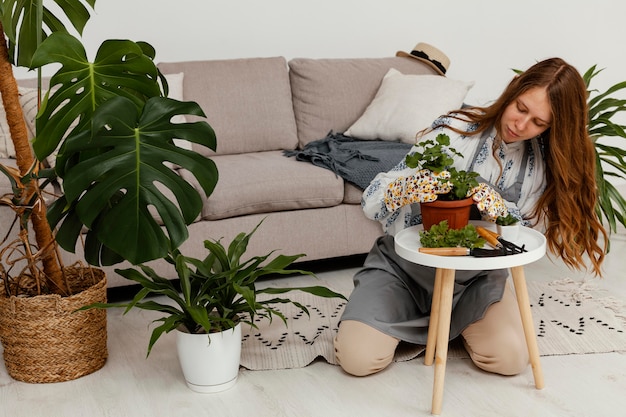 Femme à la maison avec pot de plante et outil de jardinage