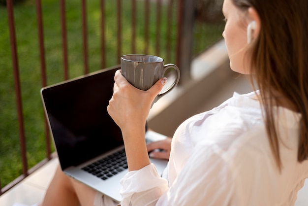 Femme à la maison en quarantaine travaillant avec un ordinateur portable et boire du café