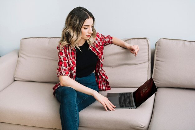 Femme à la maison à la recherche sur un ordinateur portable