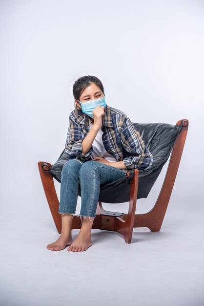 Une femme mal à l'aise assise sur une chaise et portant un masque