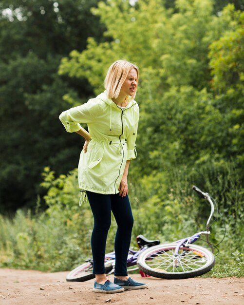 Femme avec mal de dos et vélo tombé