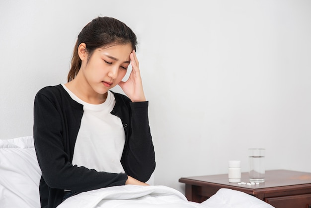 La femme malade avait mal à la tête et les mains touchaient sa tête sur le lit.