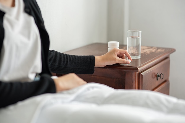 Une femme malade sur le canapé et sur le point de prendre des antibiotiques.