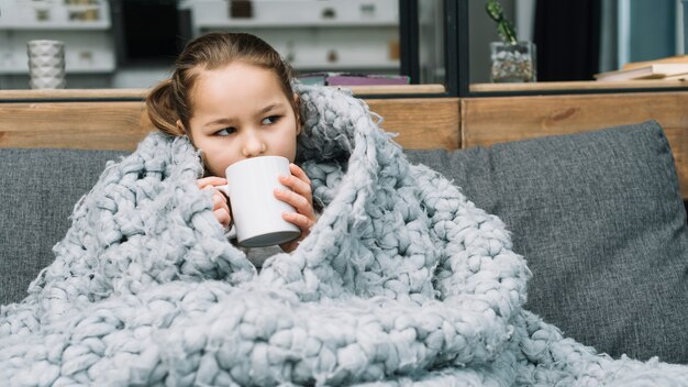 Femme malade couvrant une écharpe en laine autour d&#39;elle buvant du café dans une tasse