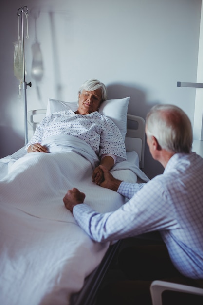 Femme malade dormir sur le lit tout homme inquiet assis à côté de son lit