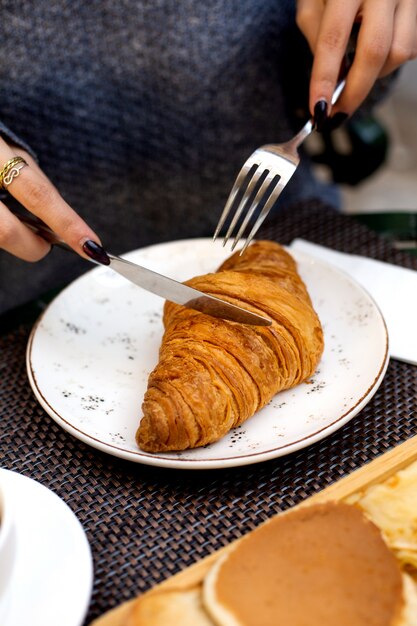 Femme, mange, croissant, couteau, fourchette