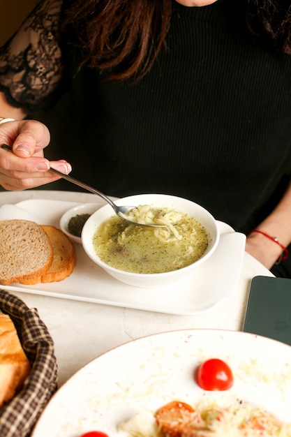 Femme mange de la soupe servie avec des herbes sèches