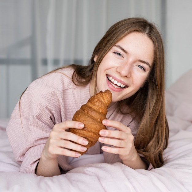 Femme mangeant un croissant au lit