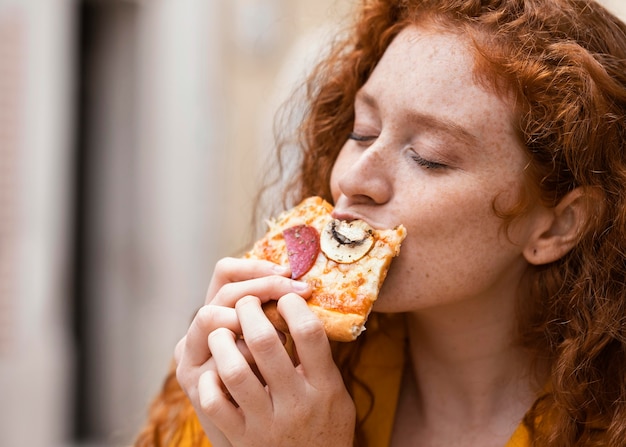 Photo gratuite femme mangeant de la nourriture de rue à l'extérieur