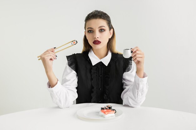 Femme mangeant des sushis en plastique, concept écologique. Perdre le monde organique.