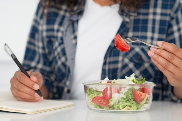 Femme, manger, salade, écrire, cahier