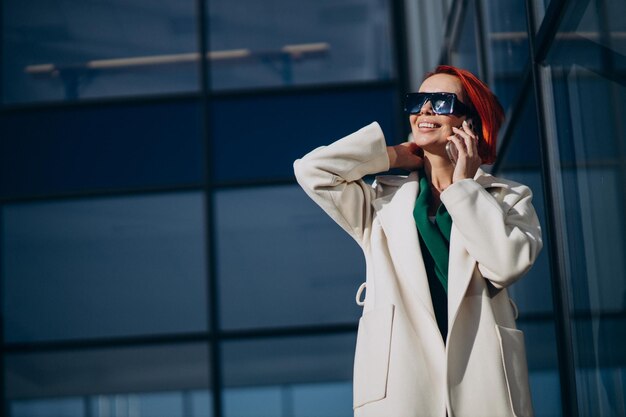 Femme en manteau à l'aide de téléphone à l'extérieur de la rue