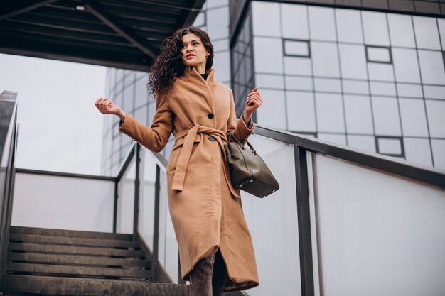 Femme en manteau beige marchant dans la ville