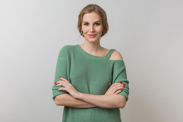 femme avec maquillage élégant et pull vert posant sur rose