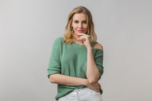 femme avec maquillage élégant et pull vert posant sur rose