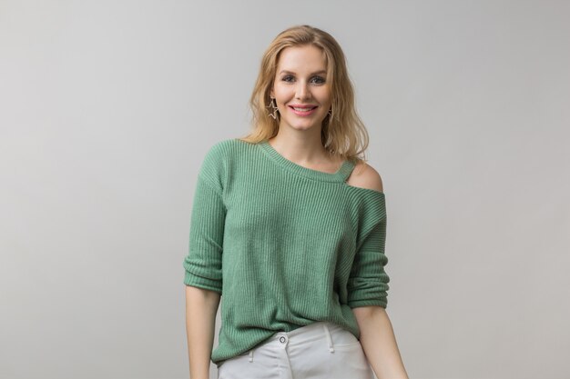 femme avec maquillage élégant et pull vert posant sur rose