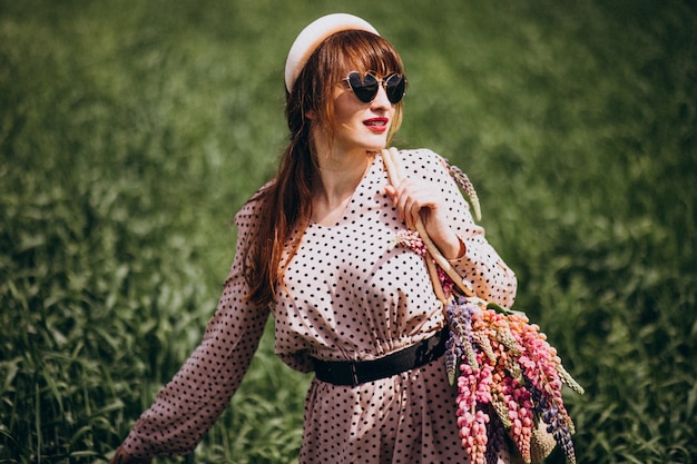 Femme marchant dans un champ avec des lupinus