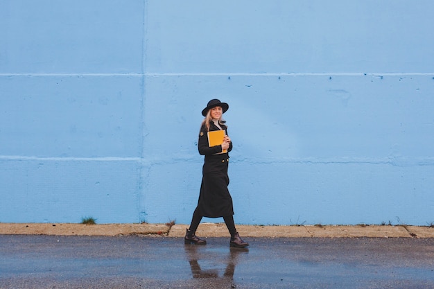 Photo gratuite femme marchant devant le mur bleu