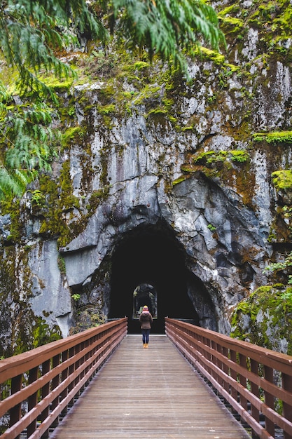 Photo gratuite femme marchant à l'intérieur d'un tunnel naturel à travers un pont