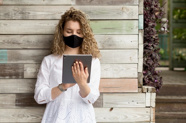 Femme avec masque à l'aide de tablette