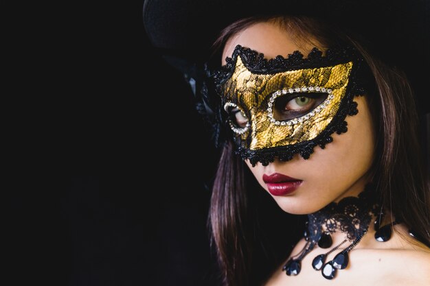 Femme avec un masque de carnaval sur un fond sombre