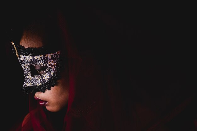 Femme avec un masque de carnaval sur un fond sombre