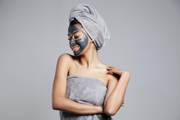 Femme avec un masque facial à l'argile de charbon gris sur