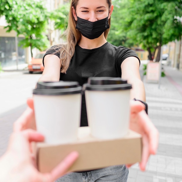 Femme avec masque facial recevant des boissons chaudes