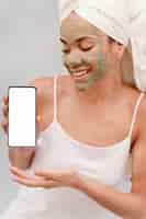 Photo gratuite femme avec masque facial tenant un smartphone vierge