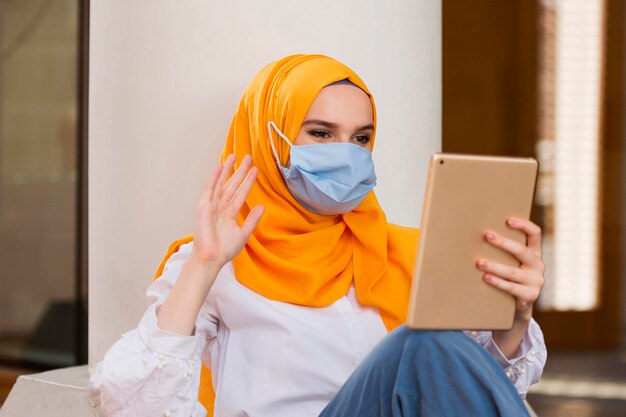 Femme avec masque médical tenant la tablette