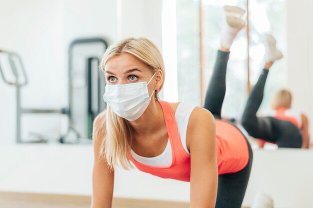 Femme avec masque médical travaillant à la salle de sport