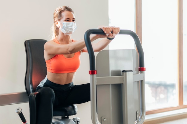 Femme avec masque médical travaillant à la salle de sport