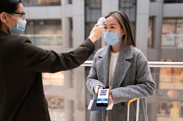 Femme avec masque tenant un thermomètre