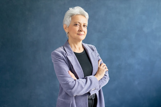 Femme mature aux cheveux gris posant avec veste violette