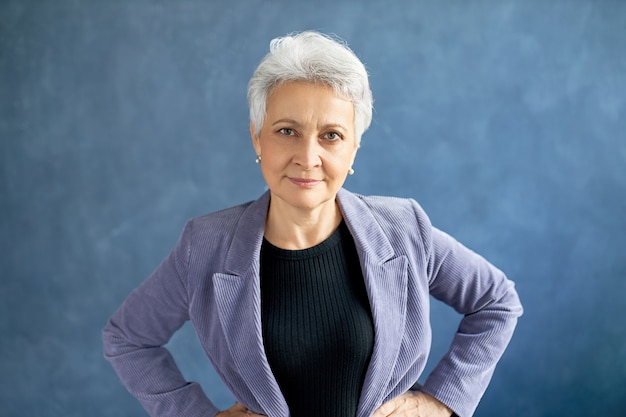 Femme mature aux cheveux gris posant avec veste violette