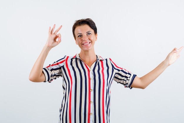 Photo gratuite femme mature en chemisier rayé montrant des signes ok et à la vue de face, joyeuse.