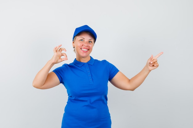 Femme mature montrant le geste ok, pointant vers l'extérieur en t-shirt et à la joyeuse.