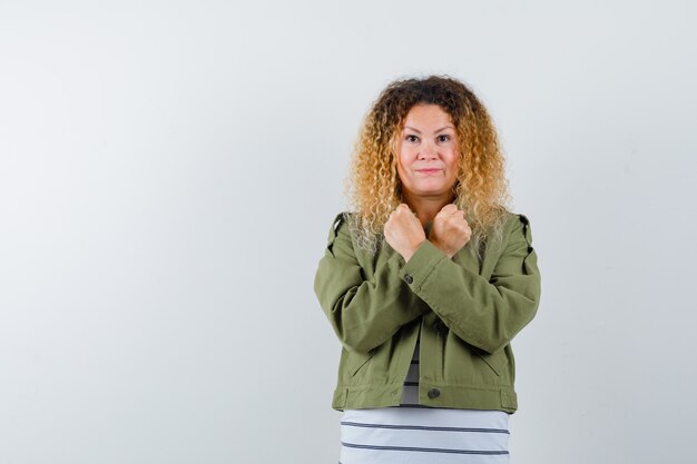 Femme mature montrant le geste de protestation en veste verte, t-shirt et à la vue de face, confiant.