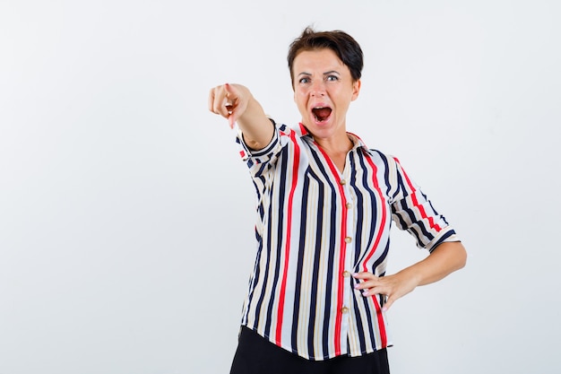 Femme Mature Montrant Quelque Chose De Loin En Chemise Rayée Et à La Vue De Face, Excité.