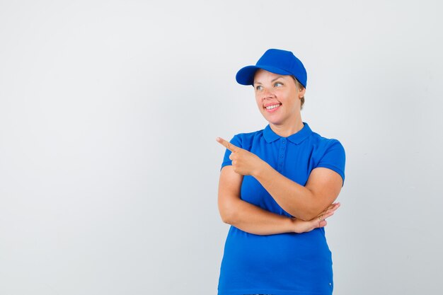 Femme mature pointant vers le coin supérieur gauche en t-shirt et à la joyeuse.