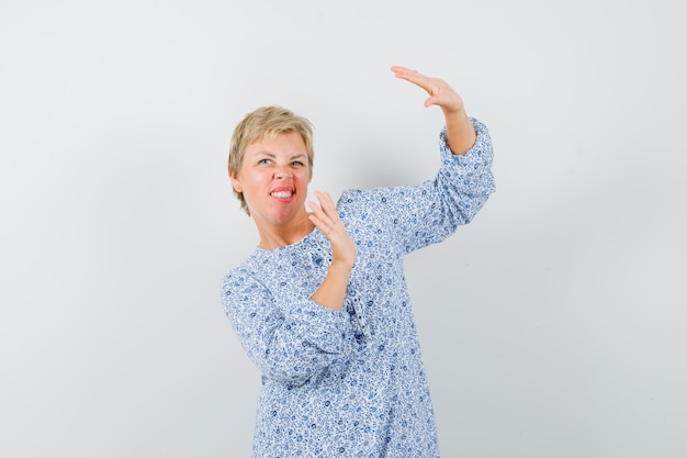 Femme mature en robe levant les mains pour se défendre et à la peur