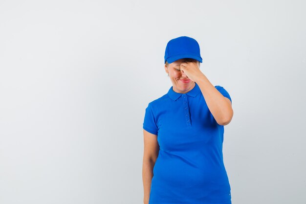 Femme mature se frottant les yeux et le nez en t-shirt et à la fatigue.