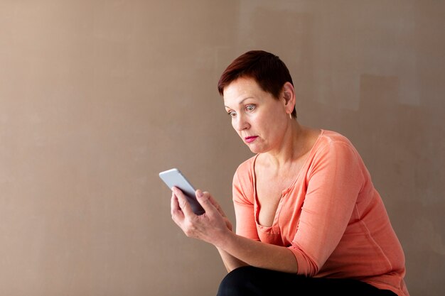 Femme mature avec un smartphone surpris