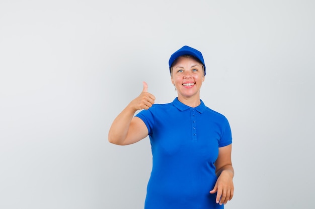 Femme mature en t-shirt bleu montrant le pouce vers le haut et à l'optimiste