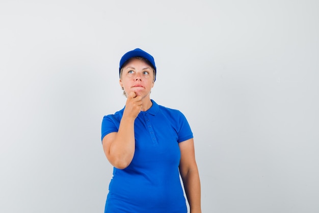 Femme mature tenant la main sur le menton en t-shirt et à l'indécision