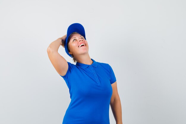 Femme mature tenant la main sur la tête en t-shirt bleu et à heureux