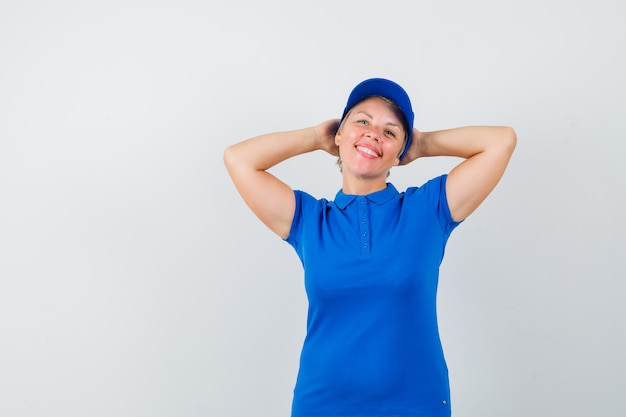 Femme mature tenant les mains derrière la tête en t-shirt bleu et à la détente.